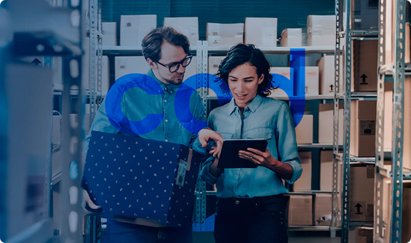 Foto com uma mulher e um homem olhando para um tablet em um centro de distribuição de produtos, rodeados por caixas, e logo do COD transparente.