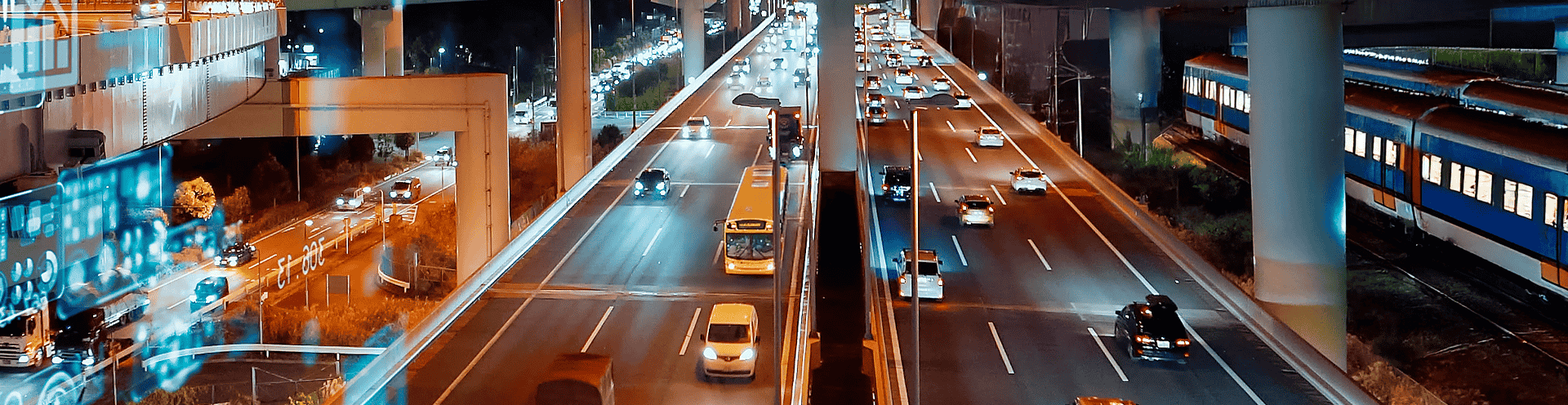 Vista noturna de rodovia movimentada com corredor de ônibus e linha férrea paralela, representando a
        integração entre modais de transporte urbano.